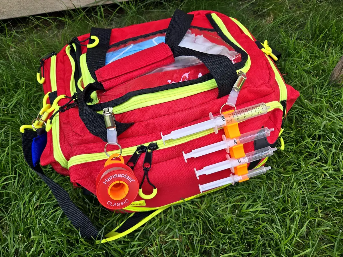Notfallrucksack mit QuickAid Spritzenhalter und Abroller im Gras